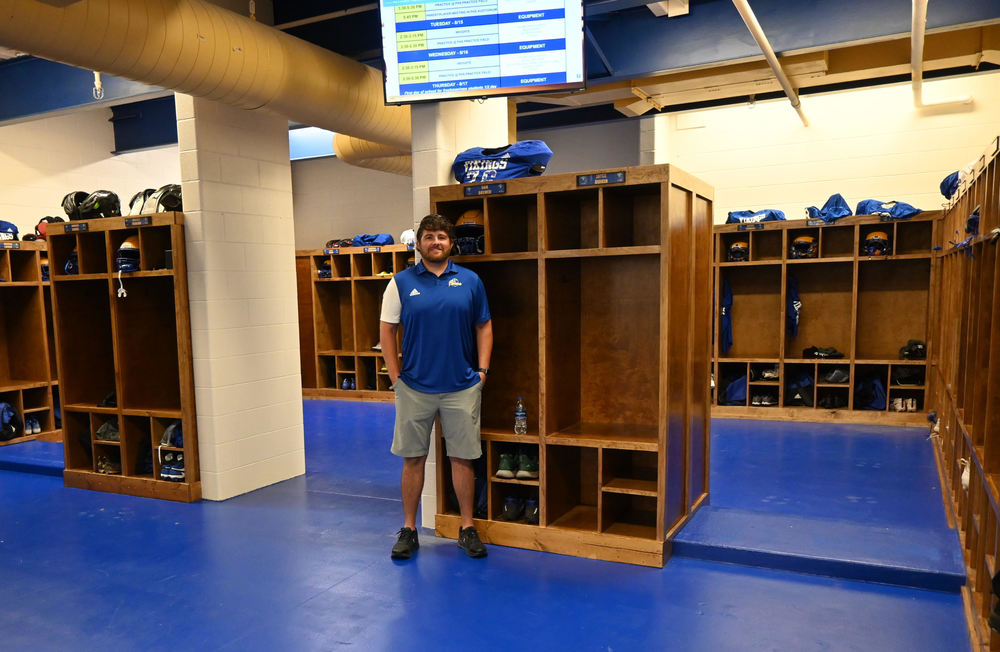 Parsons High School Head Football coach Jeff Schibi stands in front of athletic wood lockers he built for the varsity locker room. 