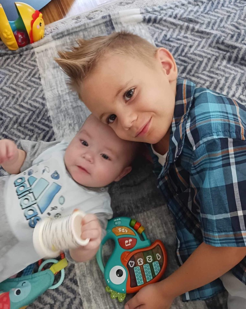 Kamen Hennen, 5,  leans in to place his head next to his baby brother's.
