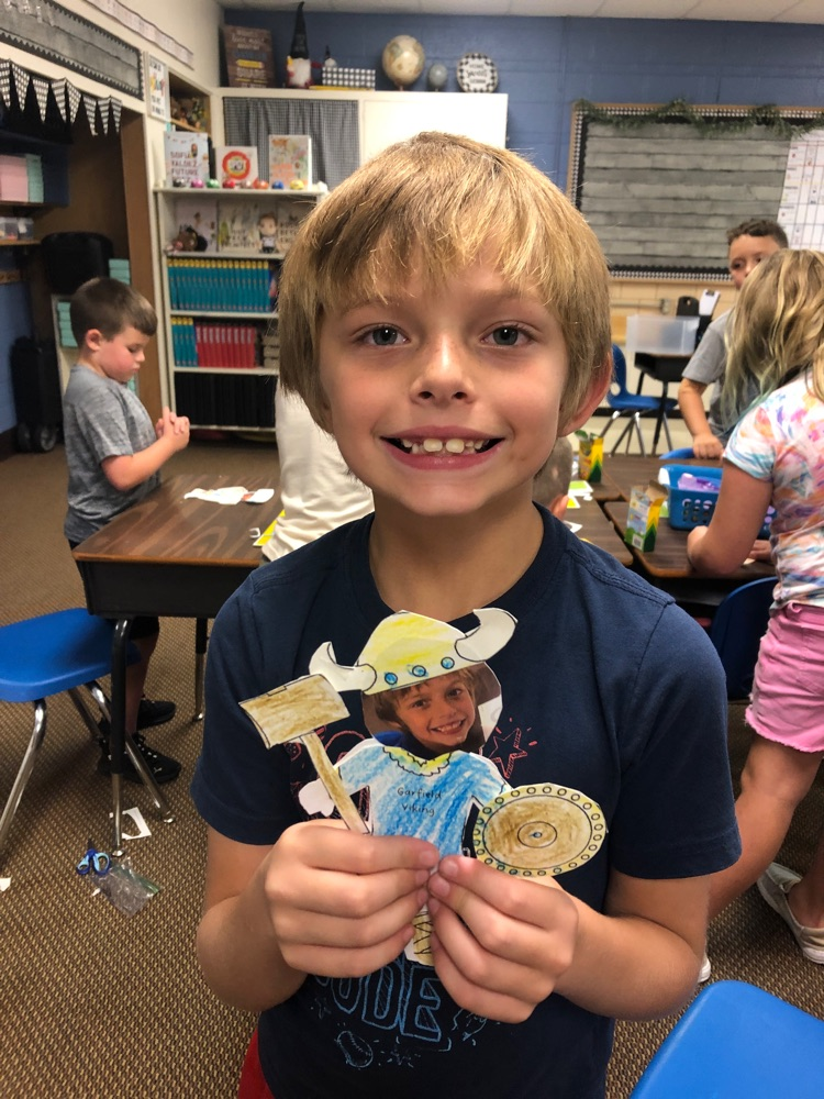 Student holding a paper Viking that has their picture as the face. 