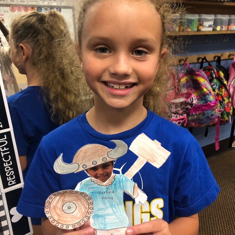 Student holding a paper Viking that has their picture as the face. 