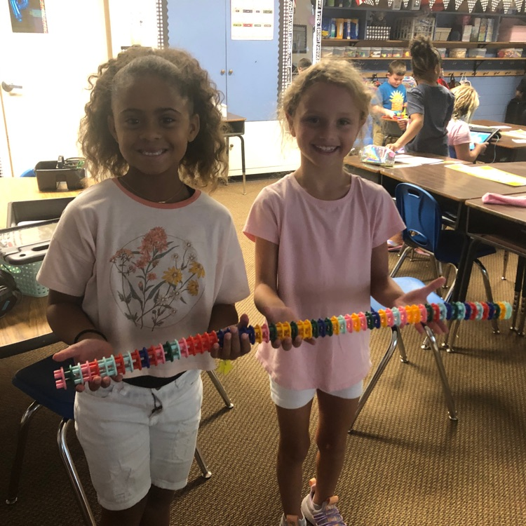 girls with a long chain of building pieces connected together 