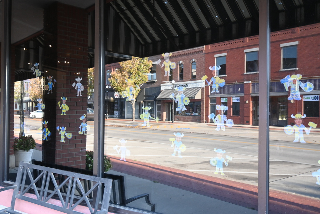 Paper vikings with kids faces glued on them fill part of a window of a downtown business.