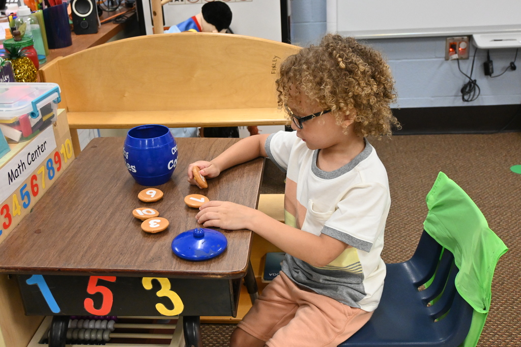 A student places plastic cookies with numbers on the back of them into a cookie jar.