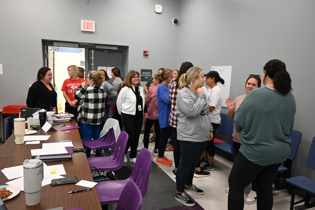 Small groups of teachers stand and discuss the answer to a question.