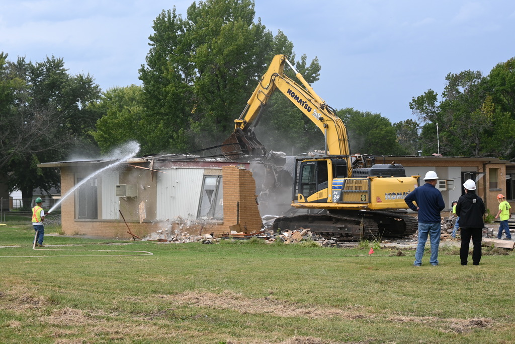 A man from DSC and Lori Ray look on as the excavator pulls metal from the roof of Washington School.
